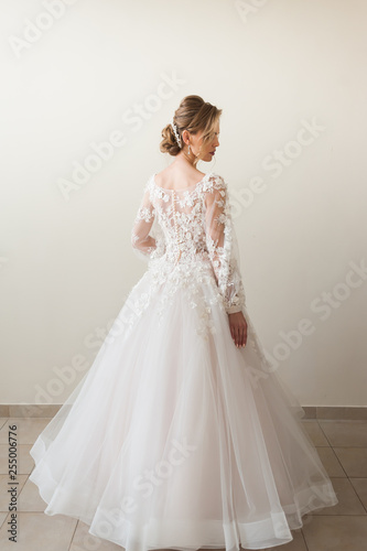 Beautiful bride wearing fashion wedding dress with feathers with luxury delight make-up and hairstyle, studio indoor photo shoot