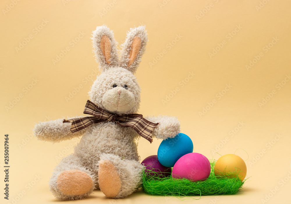 Fototapeta premium Handmade Bunny and Easter Colored Eggs. Beige background. 