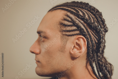 male hairstyle close-up braids, hair braided, pensive look, man portrait