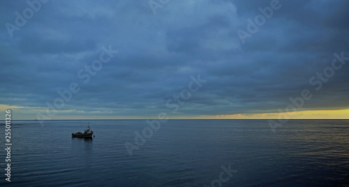 A lone boat is moored on a flat sea at sunrise