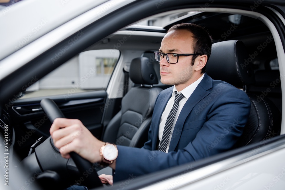 Businessman with glasses driving a car