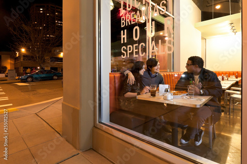 Multiethnic group of friends people customers having fun together dining out in cafe restaurant at night photo