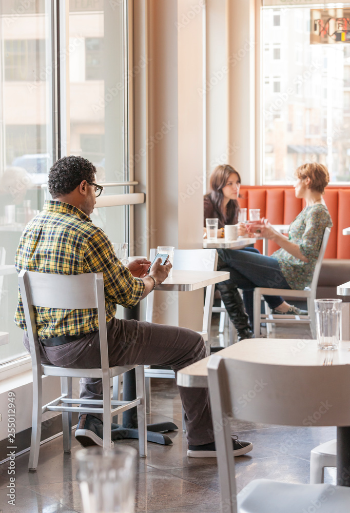 © ML Harris - People man using mobile cell phone with wifi in cafe restaurant