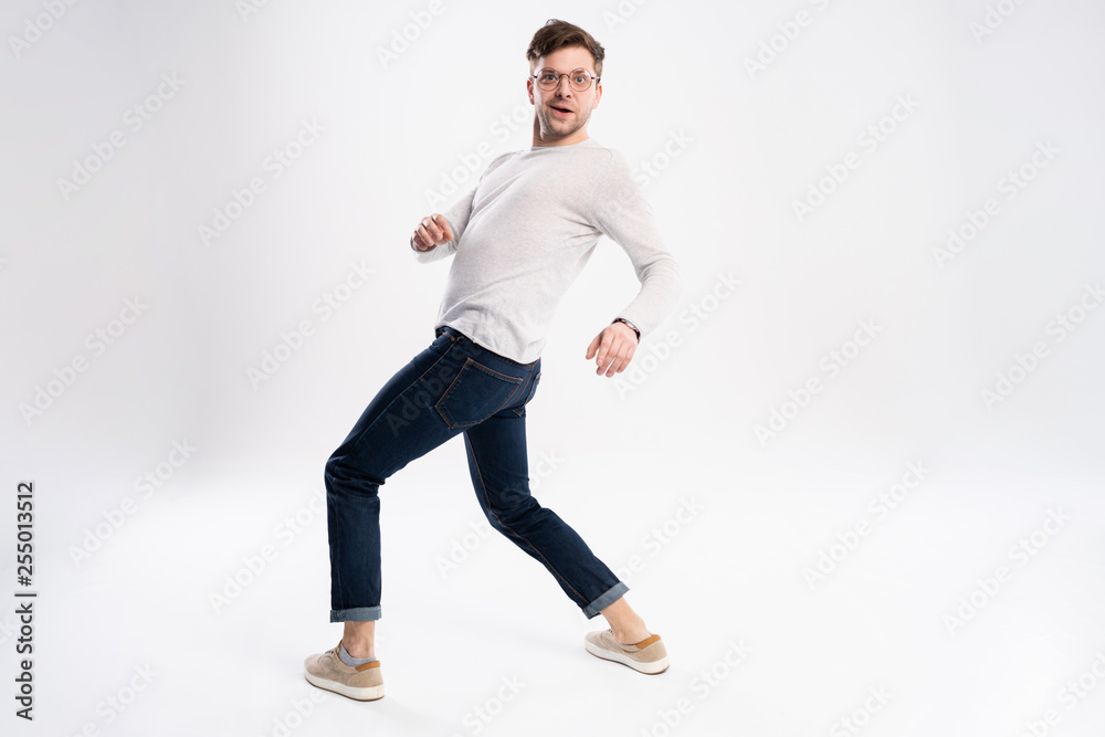 Funny man in casual is having some fun. He is posing and dancing. Isolated on white background.