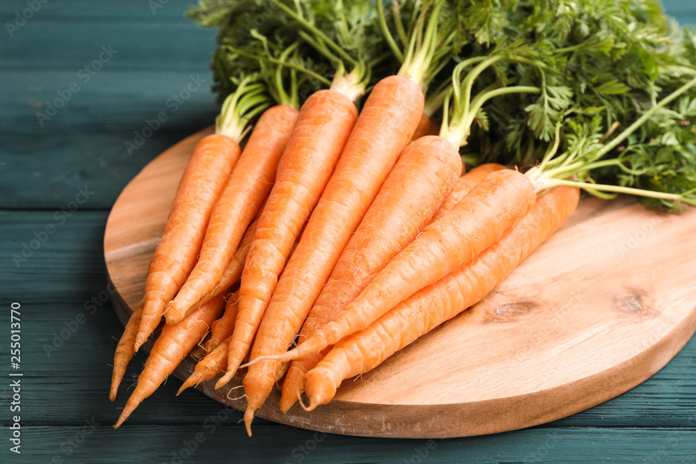 Cutting board with ripe carrots on wooden table Cutting board with ripe carrots on wooden table