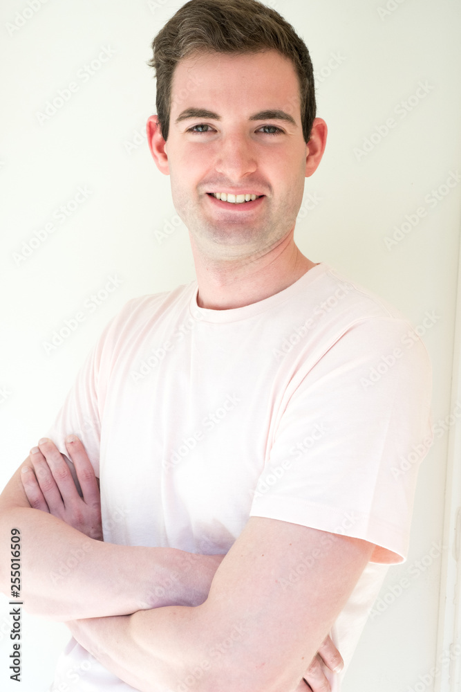 Handsome man stands with his arms crossed looking and camera and smiling posing for a portrait. Cute guy in t-shirt with arms folded, healthy and fit model. Handsome man stands with his arms crossed looking and camera and smiling posing for a portrait. Cute guy in t-shirt with arms folded, healthy and fit model.