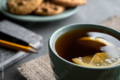 tea with lemon, peanuts cookies and gray notebook with pen and pencil