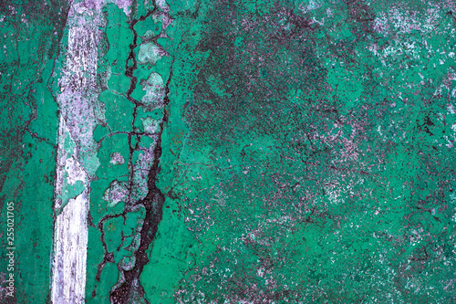 Green cracked asphalt with white line, top view photo. Cement floor top view texture. Rustic surface vintage background