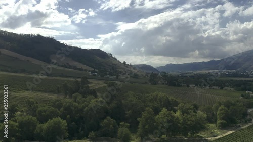 Aerial pan with greanery in front clouds and mountain behind photo