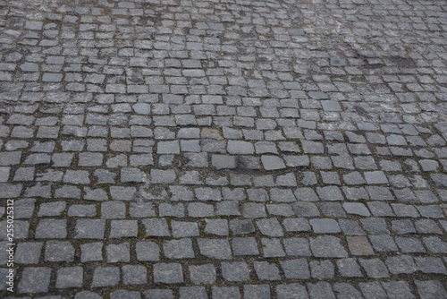 gray stone texture of old square paving tiles on the road