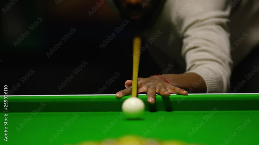 Handsome black male concentrates as he breaks to start in a game of billiards or pool