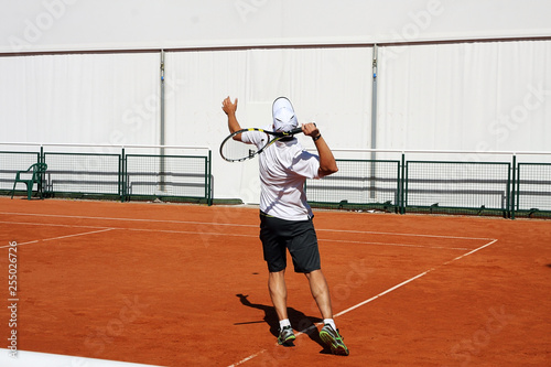 Tenisista na korcie w trakcie gry, wymachuje rakietą