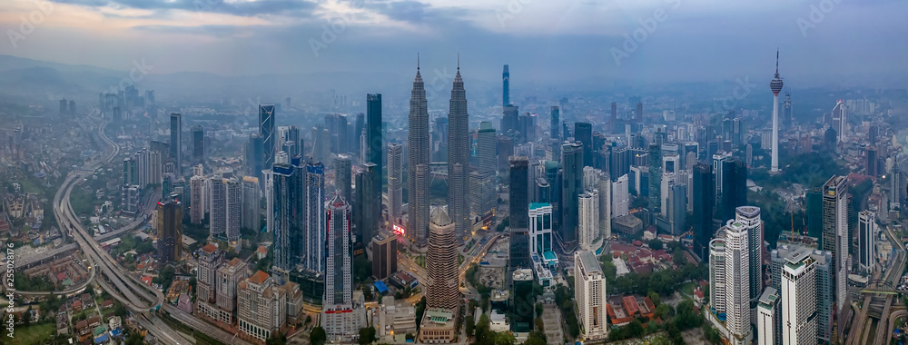 Fototapeta premium Kuala Lumpur, Malezja - 9 marca 2019: Dramatyczne zdjęcie panoramiczne z lotu ptaka panoramę miasta Kuala Lumpur podczas mglistego wschodu słońca.