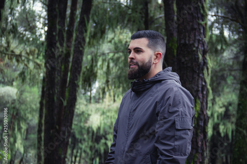 Smiling hipster in forest. Young man on sports clothes wandering in natural environment