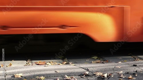 Detail of an orange modern tram bottom leaving the stop