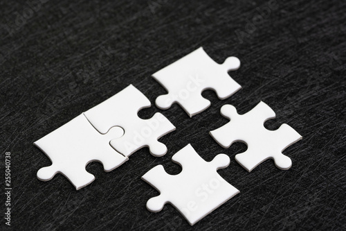 Closed up of white jigsaw puzzle on dark black background using as answer, solution, completion or strategy for business success