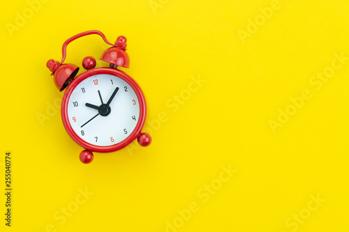 Flat lay or top view of red alarm clock on vivid yellow background with copy space using as reminder, schedule plan, time deadline or self discipline concept.