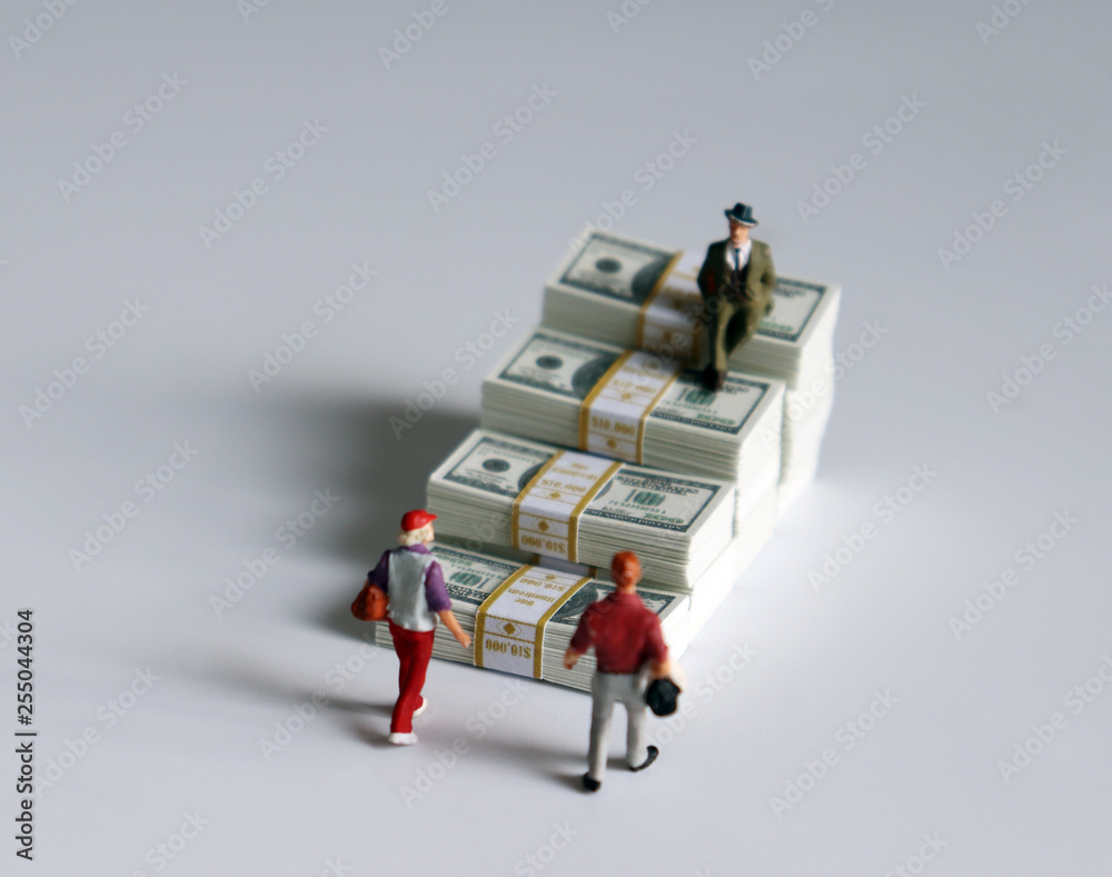 Miniature people and a pile of banknotes stacked in the shape of a staircase. Miniature people and a pile of banknotes stacked in the shape of a staircase.