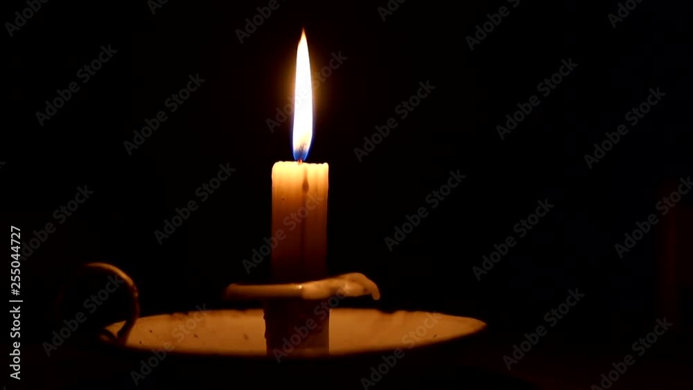 Close up footage of a candle being lit in a dark room during a power