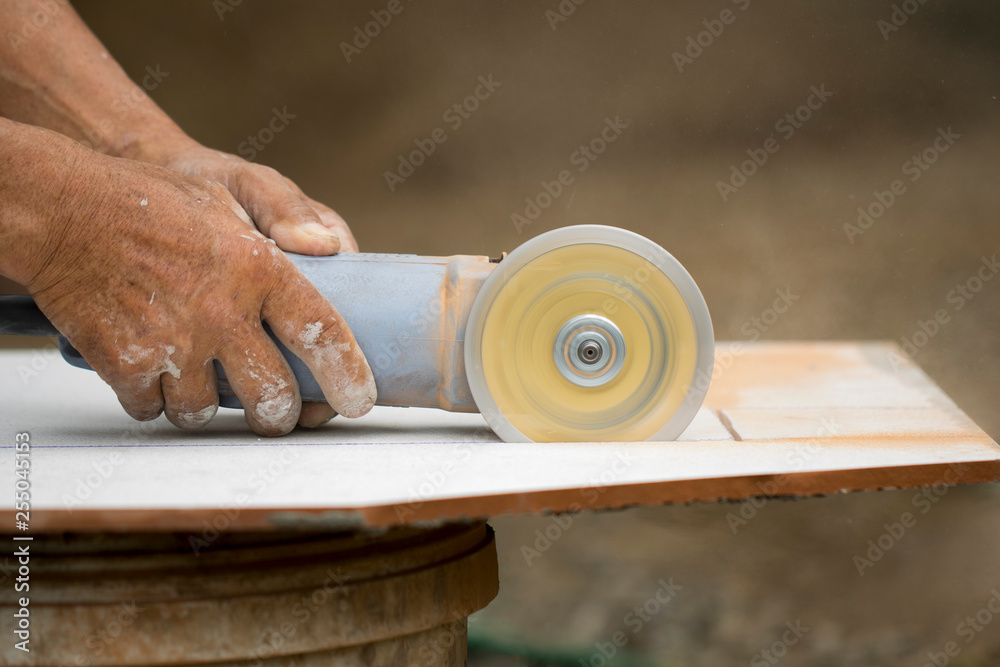Fototapeta premium Image of worker using tool to cut white tile.