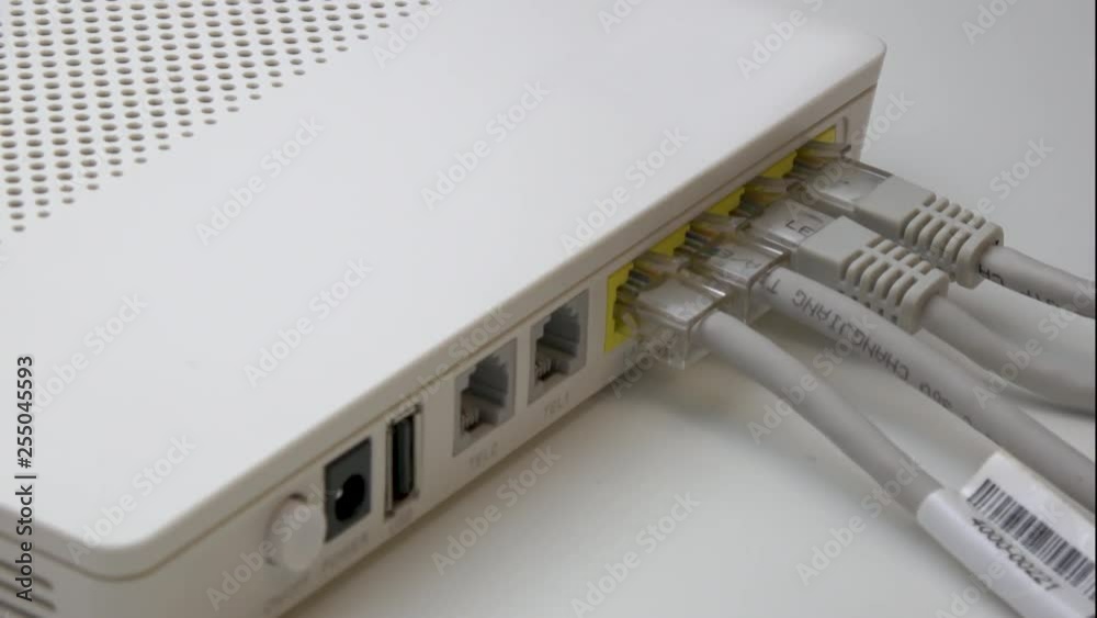 Hand Plugging and Connecting Fourth Ethernet Cable Wire Cords To White WiFi Router, Side Shot Hand Plugging and Connecting Fourth Ethernet Cable Wire Cords To White WiFi Router, Side Shot
