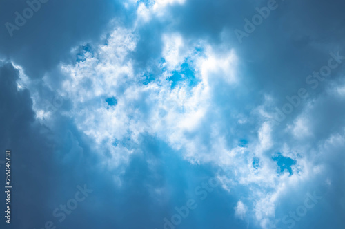Blue sky with white clouds and gray cloud blue sky on a bright day with white clouds coming in floating come to cover sun causes a white beam causing beauty in the sky.