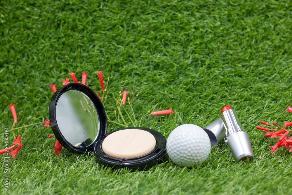 Naklejka premium Golf ball with powder and lipstick for lady golfer on green grass for golfer beauty concept