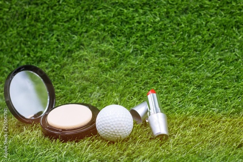 Golf ball with powder and lipstick for lady golfer on green grass for golfer beauty concept