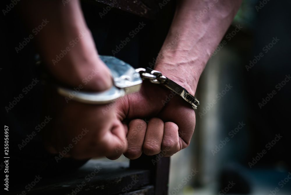 Man on the chair in Handcuffs. Rear view and Closeup ,Men criminal in handcuffs arrested for crimes. With hands in back,boy  prison shackle in the jail violence concept.