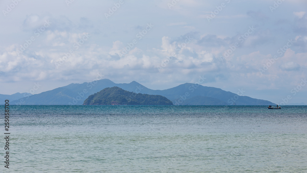 Mountain with local fisherman boat floating over the sea with bright sky in background in the afternoon at Koh Mak Island in Trat, Thailand.
