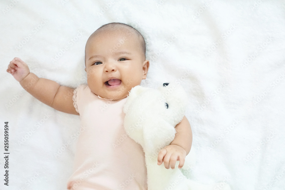 Newborn baby girl hug and cuddling her dog doll on white background Newborn baby girl hug and cuddling her dog doll on white background