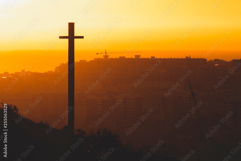 Silhouette of the Cross at sunrise over the city