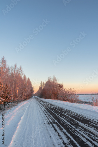 Snow-covered road in rural Russia of a frosty morning, around a field and forest