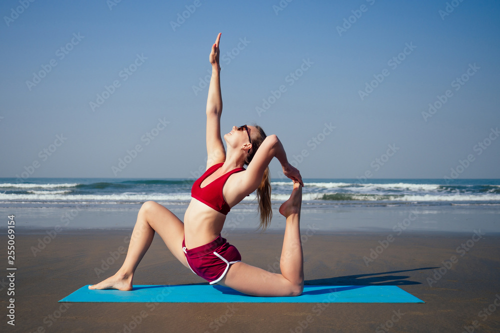 muladhara swadhisthana manipula tantra yoga on the beach woman meditates  sitting on the sand yoga mat by the sea at summer morning .female model  sitting on a twine and doing stretching Stock