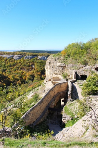 View of cavetown Chufut-Kale above autumn forest in valley near Bakhchisarai city on the Crimean Peninsula. It'is a medieval city-fortress in the Crimean Mountains that now lies in ruins.