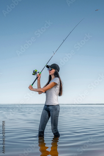 Fishing concept. Young fisherwoman with tackles at lake coast