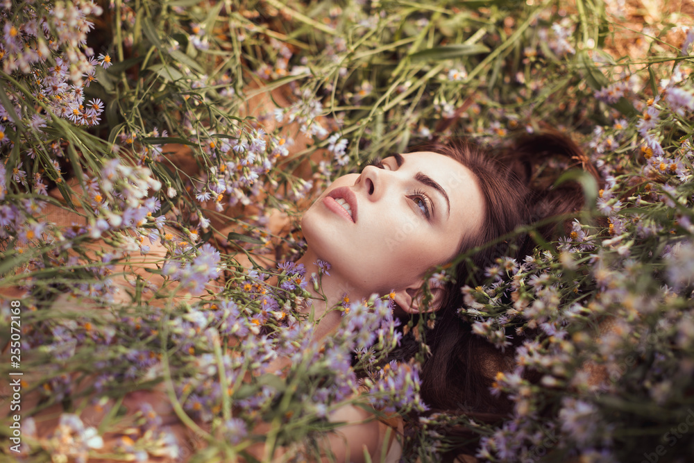 Spring. Nude sexy attractive adult woman outdoors laying on flower field