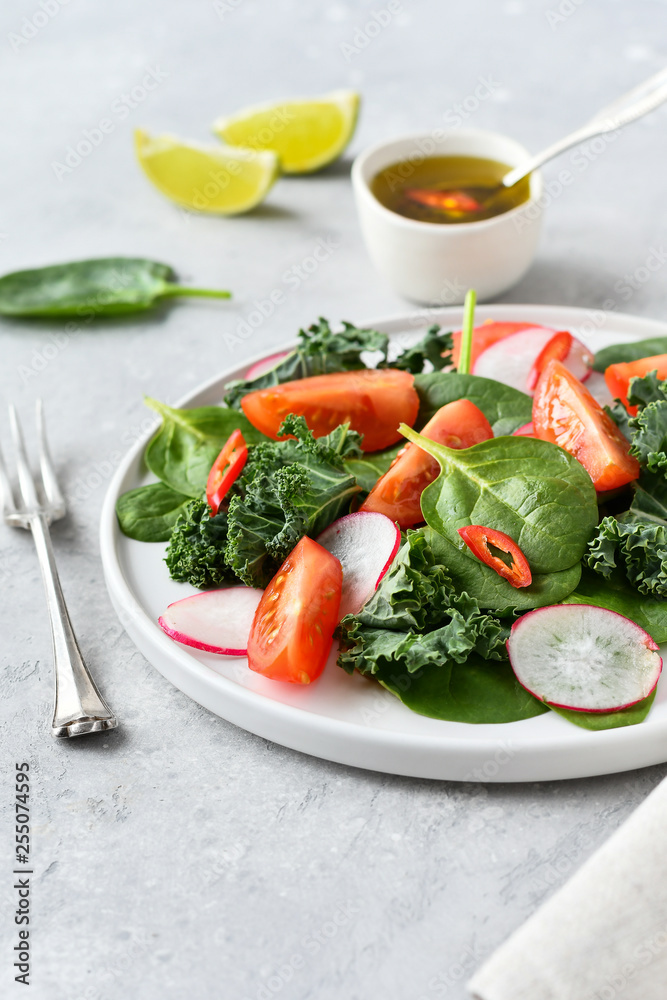 fresh salad of organic spinach, kale, tomatoes and radish with olive oil and lime juice. healthy eating concept. diet, vegan cuisine. light background, selective focus fresh salad of organic spinach, kale, tomatoes and radish with olive oil and lime juice. healthy eating concept. diet, vegan cuisine. light background, selective focus