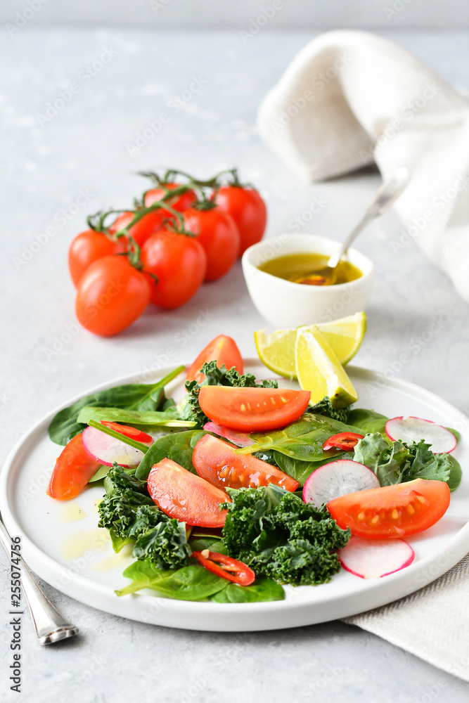 fresh salad of organic spinach, kale, tomatoes and radish with olive oil and lime juice. healthy eating concept. diet, vegan cuisine. light background, selective focus fresh salad of organic spinach, kale, tomatoes and radish with olive oil and lime juice. healthy eating concept. diet, vegan cuisine. light background, selective focus
