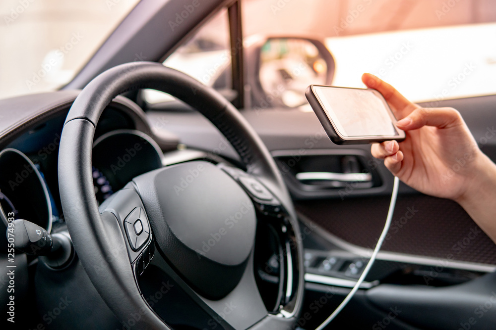 Male driver sitting with steering wheel using smartphone for GPS navigation. Mobile phone mounting with magnet on the car console in modern car. Urban driving lifestyle with mobile app technology Male driver sitting with steering wheel using smartphone for GPS navigation. Mobile phone mounting with magnet on the car console in modern car. Urban driving lifestyle with mobile app technology