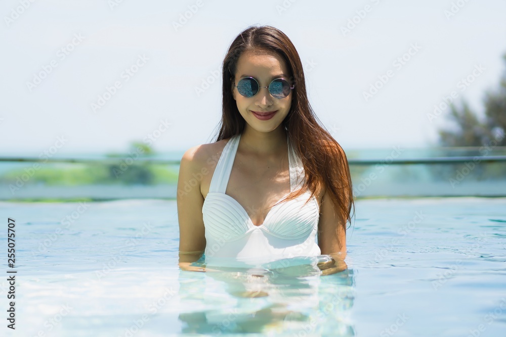 Beautiful young asian woman happy and smile in swimming pool for relax travel and vacation