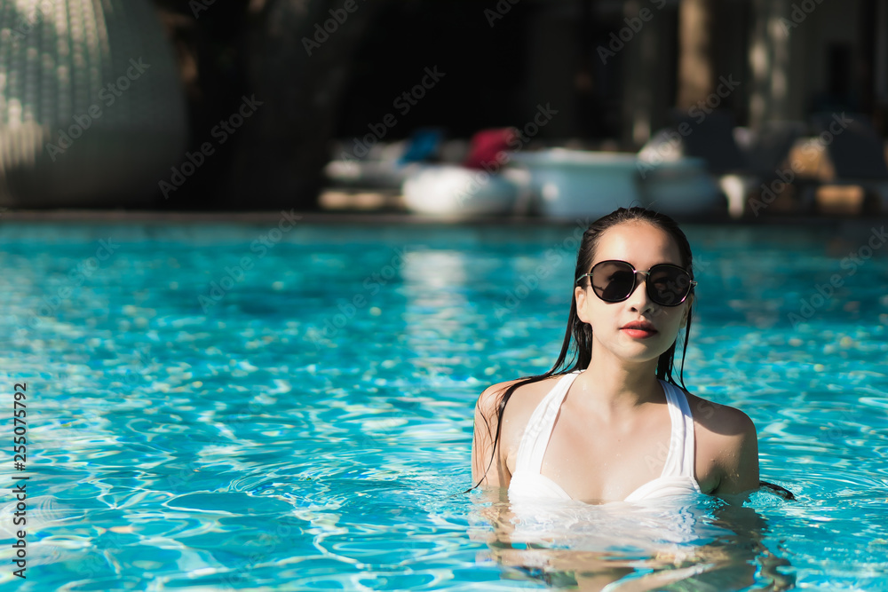 Beautiful young asian woman happy and smile in swimming pool for relax travel and vacation