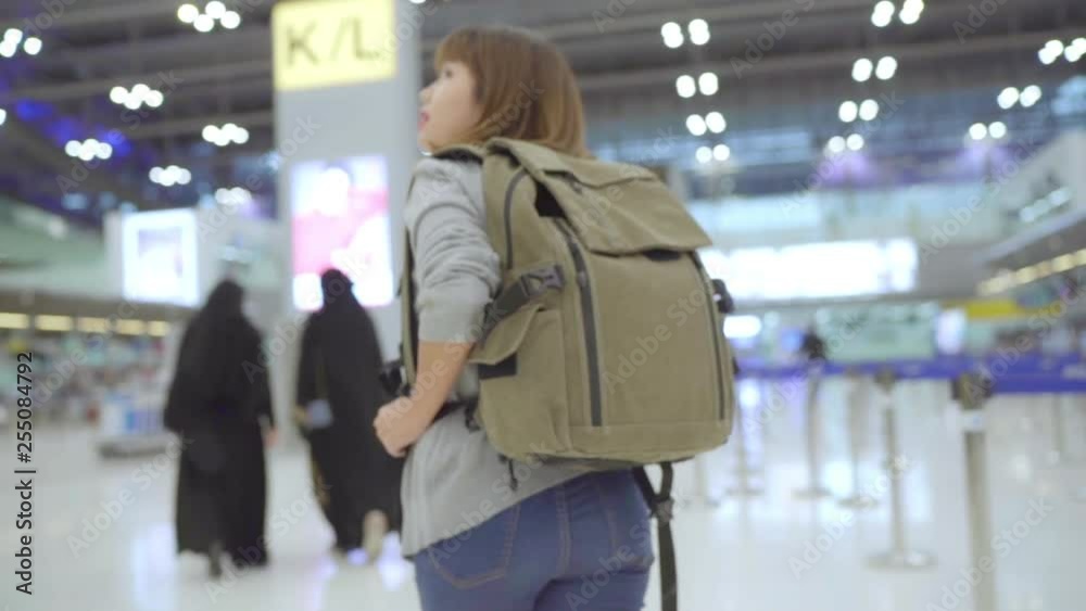 Slow motion - Young Asian backpacker woman walking in terminal hall while going to boarding flight at the departure gate in international airport. Lifestyle backpack tourist travel holiday concept.