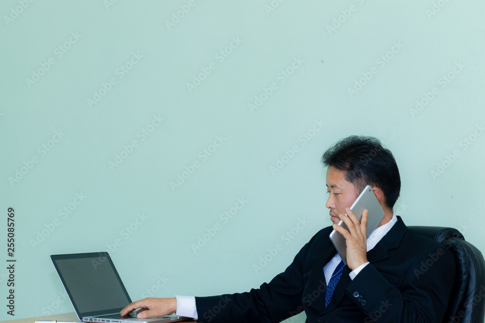 A studio image of an Asian businessman with a handsome beard and hold the tablet a mint green background A studio image of an Asian businessman with a handsome beard and hold the tablet a mint green background