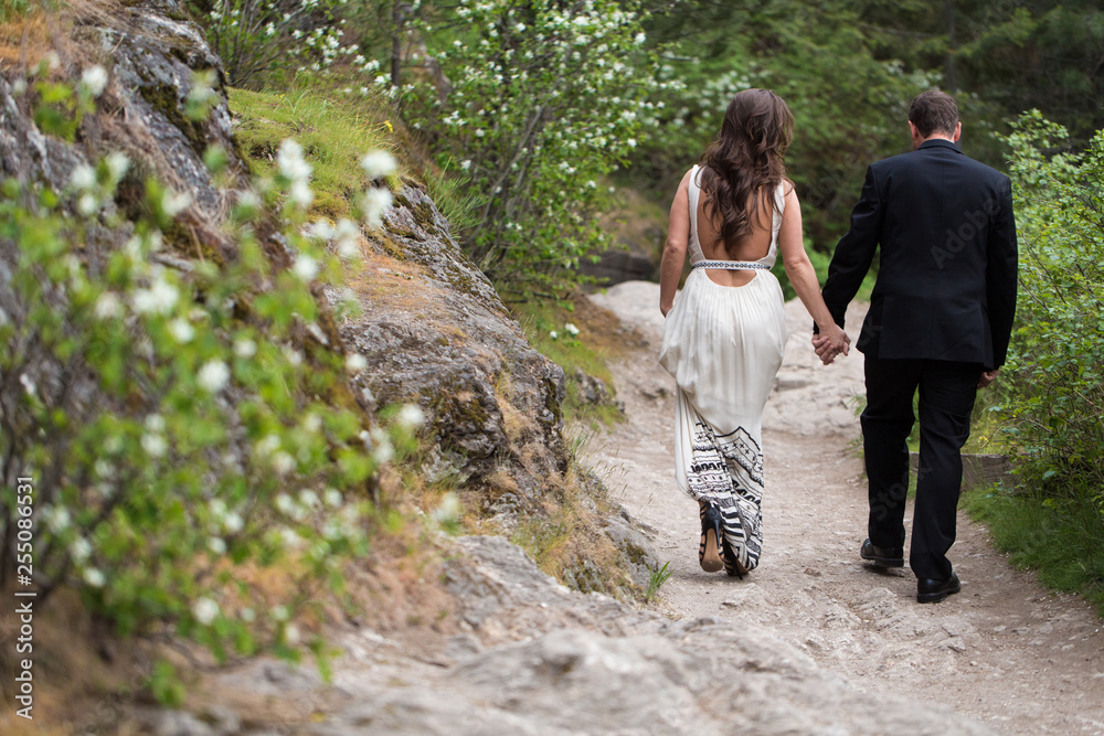 Couple walking away on path holding hands Couple walking away on path holding hands