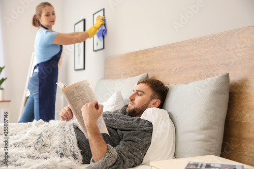 Lazy husband reading newspaper while his wife doing chores at home