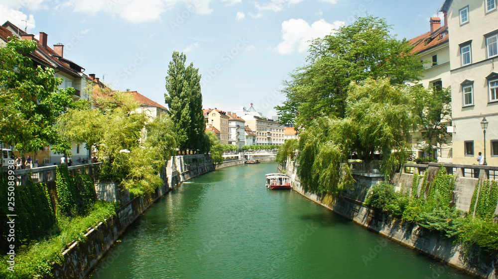 Scenic view of the Ljubljanica river in old town, cityscape with a green trees, beautiful architecture, sunny day, Ljubljana, Slovenia
