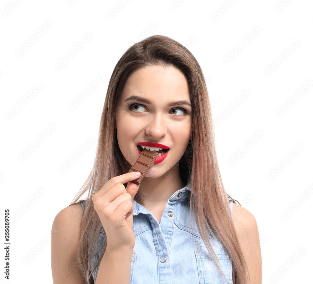 Beautiful young woman eating tasty chocolate on white background Beautiful young woman eating tasty chocolate on white background