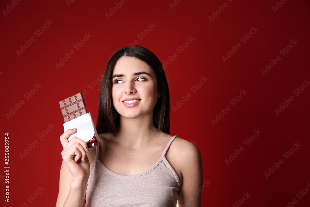 Beautiful young woman with tasty chocolate on color background Beautiful young woman with tasty chocolate on color background