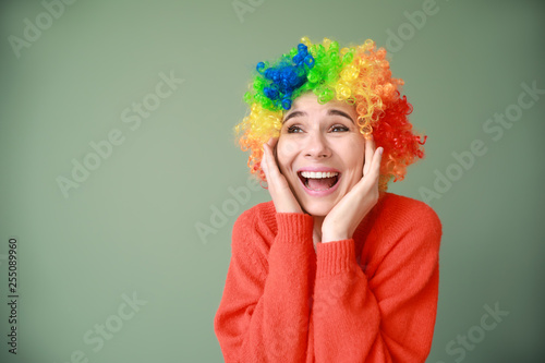 Funny woman with wig for April Fools' Day celebration on color background